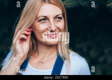 Primo piano ritratto di donna bionda dagli occhi blu in jeans con sospetti Foto Stock