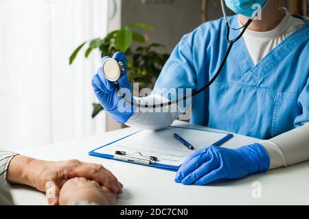 Medico generale in studio medico, medico che esegue un controllo della pressione sanguigna, ascoltando il cuore, i polmoni e gli intestini del paziente Foto Stock