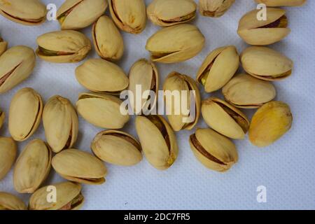 Deliziose e salutari noci verdi di pistacchio, frutta dever, pistacchi si trovano su uno sfondo bianco opaco. Foto Stock