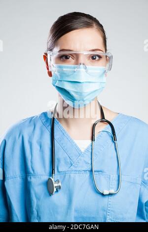 Giovane donna seria EMS UK Key operaio medico, ritratto isolato Sfondo bianco della struttura ICU, indossare dispositivi di protezione individuale DPI, maschera facciale Foto Stock