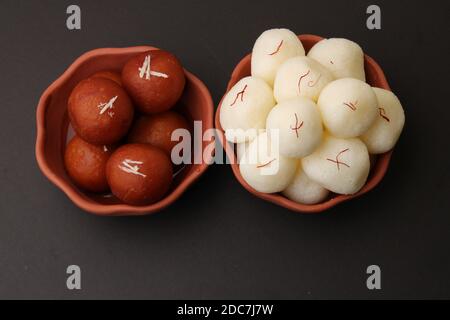 Famosi dessert indiani rasgulla/ rosogulla/ roshogulla e gulab jamun/ gulabjam serviti in terrena ciotola. Foto Stock