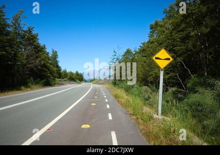 Segnale di avvertimento per la strada asfaltata in Cile. Segnale di avvertimento di postolo avanti. Foto Stock