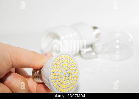 Diverse lampadine a LED e lampade fluorescenti compatte e il mano maschile su uno sfondo chiaro Foto Stock