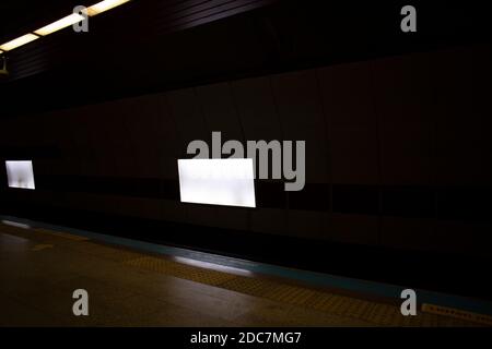 Cartelli pubblicitari appesi alle pareti all'interno della stazione della metropolitana. Foto Stock