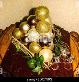 Un gruppo di varie tonalità di palline natalizie color oro, impilate in una piramide su un tavolo in legno Foto Stock