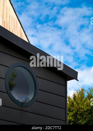 Particolare di una finestra circolare posta in un muro di legno su una casa moderna. Foto Stock