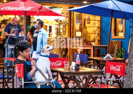 Buenos aires / Argentina; 14 novembre 2020: Donna con il suo cane che beve una soda ad un tavolo esterno in un ristorante, mantenendo la distanza sociale necess Foto Stock