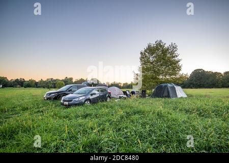 Campeggiatori Hipcamp appendere fuori tenda campeggio in campi di fattoria su il fine settimana Foto Stock