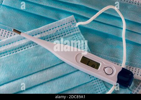 Termometro bianco su maschere chirurgiche monouso. Foto Stock