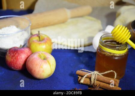 Ingredienti vari per la cottura invernale stagionale e altre ricette, miele, mele, erbe e spezie su sfondo blu scuro. Vista dall'alto. Foto Stock