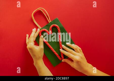 Due caramelle rosse a strisce giacciono su un pacchetto verde su sfondo rosso Foto Stock