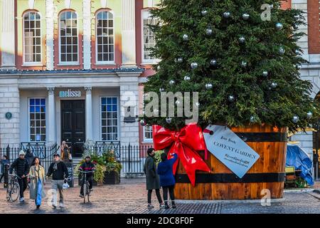 Londra, Regno Unito. 19 Nov 2020. La gente è ancora fuori e godere l'albero di Natale e le decorazioni in Covent Garden, nonostante il nuovo blocco che è ora in vigore. Le luci di Natale sono accese, ma i negozi sono chiusi, solo alcuni stabilimenti di ristorazione rimangono aperti. Molte persone indossano maschere, anche all'esterno. Credit: Guy Bell/Alamy Live News Foto Stock