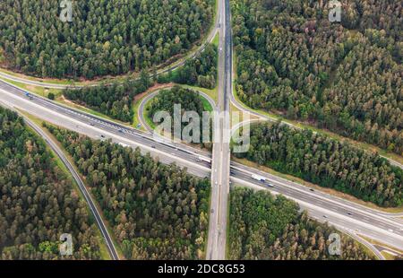 Vista aerea dell'incrocio autostradale con il traffico automobilistico. Vista dall'alto dall'alto dell'uccello, foto dell'incrocio stradale nell'ambiente forestale Foto Stock