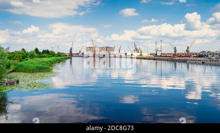 Carico, porto industriale e porto di Szczecin con magazzini, gru a banchina e macchinari industriali. Pomerania occidentale, Polonia Foto Stock