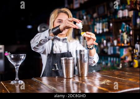 Barman donna professionista che versa una bevanda alcolica fresca nei bicchieri nei cocktail bar Foto Stock