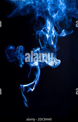 Getto di fumo blu isolato su sfondo nero. Caotico ricci di fumo di sigaretta, modello verticale per il design Foto Stock