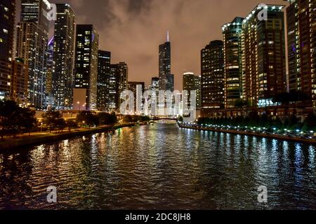 Lo skyline della grande città si illumina di notte con il fiume che attraversa Foto Stock