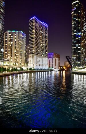 Lo skyline della grande città si illumina di notte con il fiume che attraversa Foto Stock