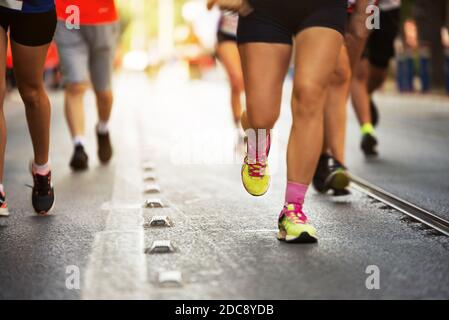 Primo piano delle gambe dei corridori Marathon su una strada asfaltata. Foto Stock
