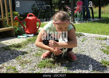 Ragazza che tiene e bacia la sua anatra nera e bianca dell'animale domestico Foto Stock