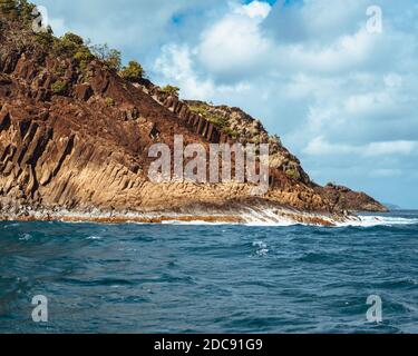 Onde che si infrangono sulle rive rocciose di Santa Lucia Foto Stock