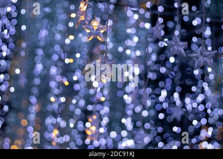 Pioggia di luci bokeh e ornamenti a forma di stella con un sfondo blu scuro Foto Stock