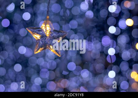 Pioggia di luci bokeh e un ornamento a forma di stella con uno sfondo blu scuro Foto Stock
