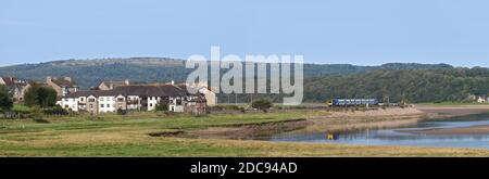 Treno Nord CAF classe 195 treno civico che passa Arnside, Cumbria che corre fuori dal viadotto riflesso nel fiume Kent Foto Stock