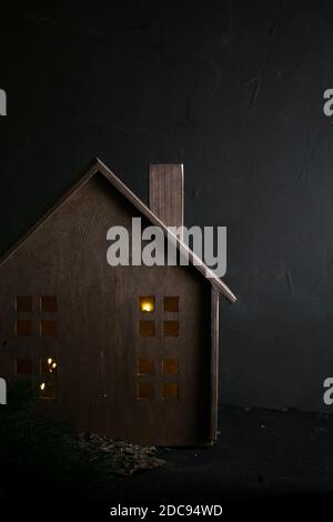 Piccola casa giocattolo di legno con luci all'interno delle finestre con i rami di pino Foto Stock