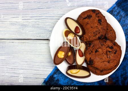 Cioccolatini e biscotti croccanti al cioccolato si trovano su un piatto bianco. Stile provenzale Foto Stock