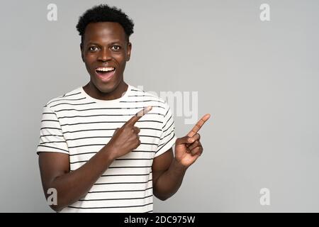 Ridendo uomo nero in t-shirt spogliata punta via con le dita, guardare la fotocamera, mostrando spazio vuoto per la pubblicità, l'offerta, il prodotto, promotio Foto Stock