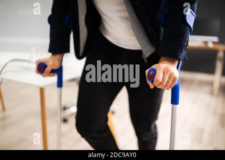 Uomo disabile in piedi con stampelle in ufficio Workplace Foto Stock