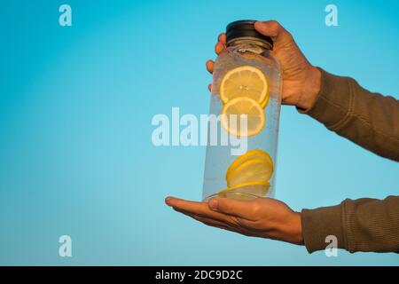 Uomo che tiene una bottiglia grande di acqua dolce al limone. Bevande sane, dieta e concetto di detox Foto Stock