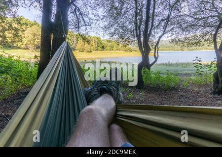 Rilassati in un'amaca tra gli alberi mentre guardi un lago Foto Stock