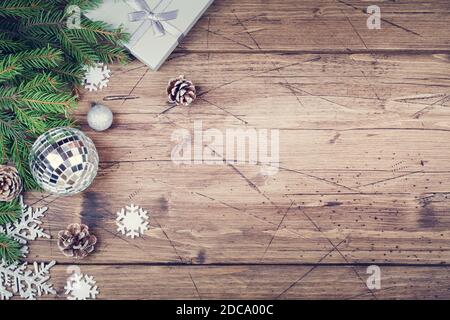 rami di abete , dono , coni, fiocchi di neve e palle da discoteca su sfondo di legno marrone, spazio di copia vista dall'alto. Natale e Capodanno Foto Stock