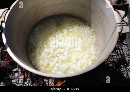 Friggere cipolle in olio in calderone sul fuoco per pilaf Foto Stock