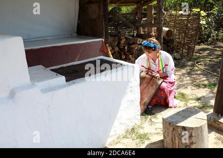 Donna accende fuoco in stufa russa in cortile Foto Stock