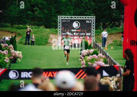 KHARKIV, UCRAINA - 2 AGOSTO 2020: Kharkiv triathlon Via di ferro. Il corridore dopo la transizione al ciclismo. Triatleta che corre in tuta triathlon tr Foto Stock