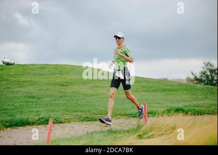 KHARKIV, UCRAINA - 2 AGOSTO 2020: Kharkiv triathlon Via di ferro. Il corridore dopo la transizione al ciclismo. Triatleta che corre in tuta triathlon tr Foto Stock