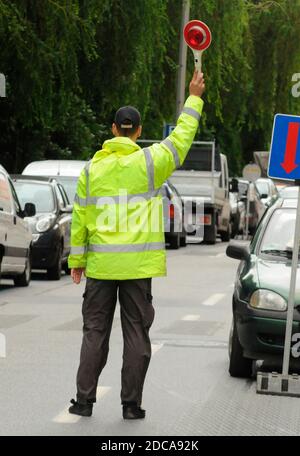 controllore del traffico in giubbotto di sicurezza che regola il traffico sulla strada Foto Stock