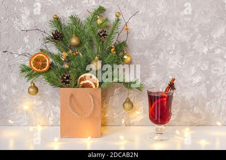 Albero di Natale decorato sfere d'oro, coni in pacchetto artigianato, luci garland e bicchiere di vino caldo VIN brulé con spezie sul tavolo. Natale o Capodanno, vinci Foto Stock