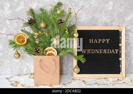 Happy Mercoledì testo su bordo nero lettera e bouquet festivo di rami di abete con decorazione di natale in pacchetto artigianale sul tavolo. Modello per cartolina, Foto Stock