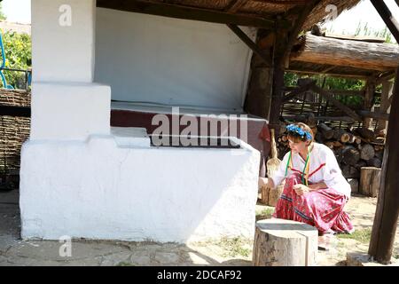 Cossack donna accende fuoco in stufa russa in cortile Foto Stock