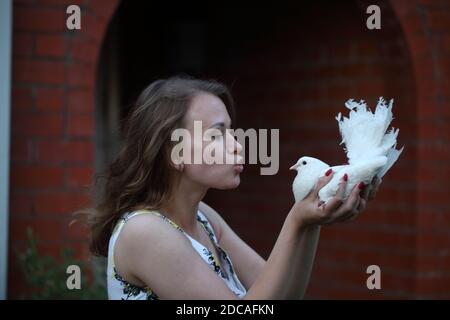 Felice ragazza con una colomba bianca nelle sue mani Foto Stock
