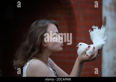 Felice ragazza con una colomba bianca nelle sue mani Foto Stock