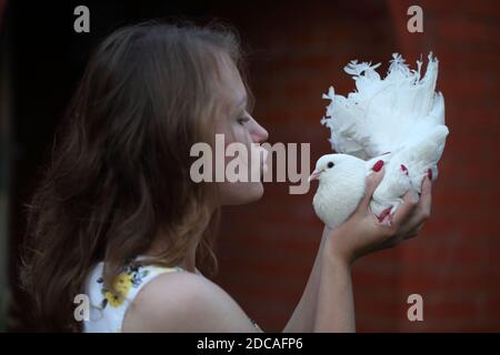 Felice ragazza con una colomba bianca nelle sue mani Foto Stock