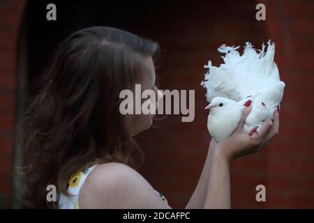 Felice ragazza con una colomba bianca nelle sue mani Foto Stock