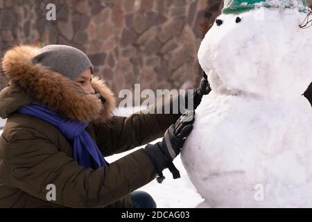 Una ragazza fa un pupazzo di neve nel cortile in winter.the concetto di attività invernale per bambini Foto Stock