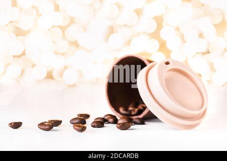 Bella tazzina da asporto fatta di cioccolato con chicchi di caffè versato su sfondo dorato di natale luci bokeh. Mockup per il design decorativo. Chris Foto Stock