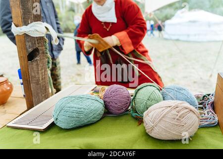 Tessitura artigianale. Donna in abito tradizionale lavora con le mani Foto Stock